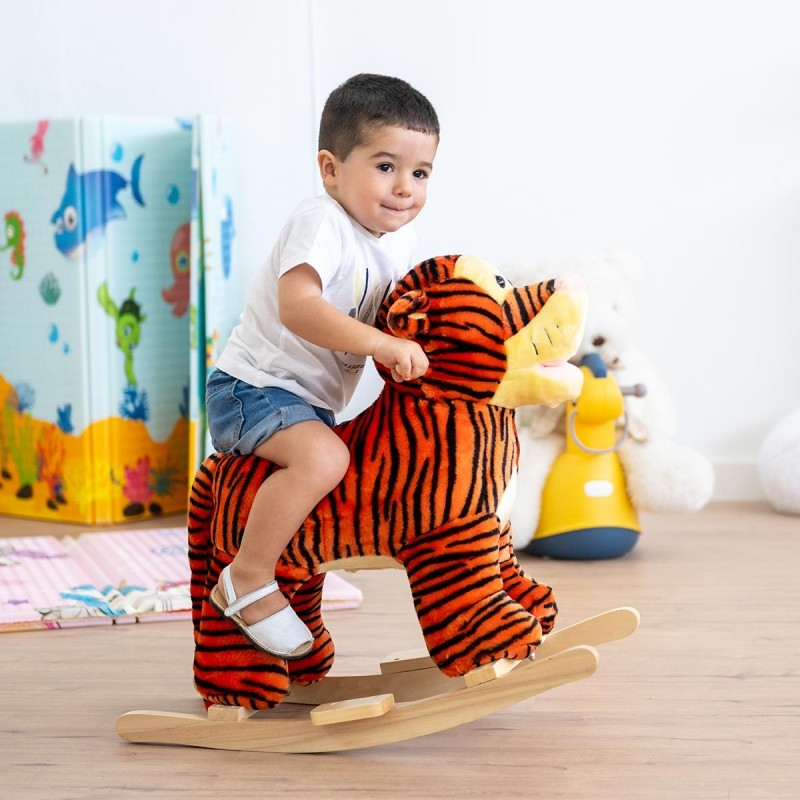 Criança em cavalo de balanço de peluche tigre com base de madeira clara em quarto infantil