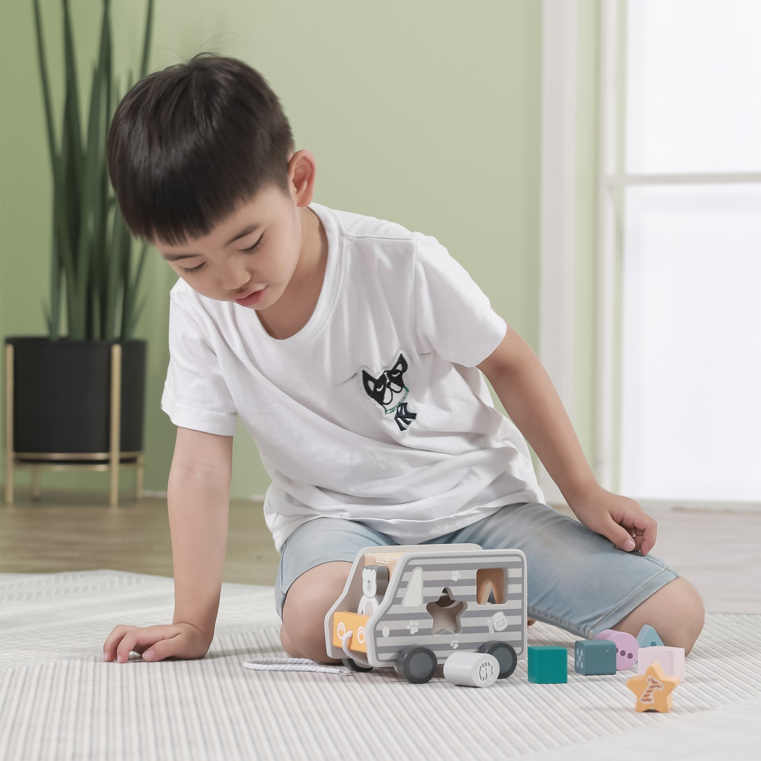 Menino sentado a brincar com brinquedo de madeira e blocos coloridos.