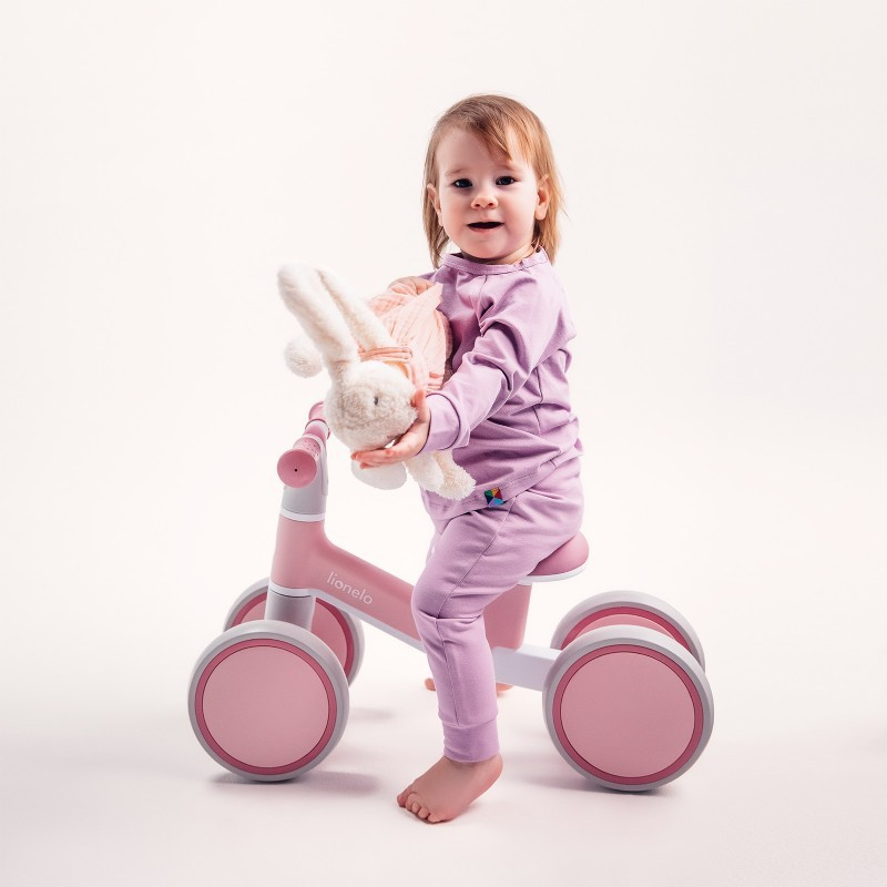 Bebé num triciclo rosa segurando coelho de peluche