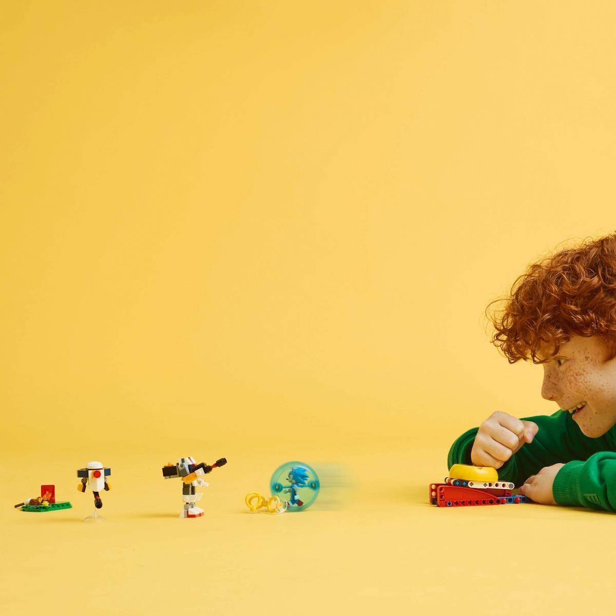 Criança a brincar com brinquedos LEGO pequenos sobre fundo amarelo