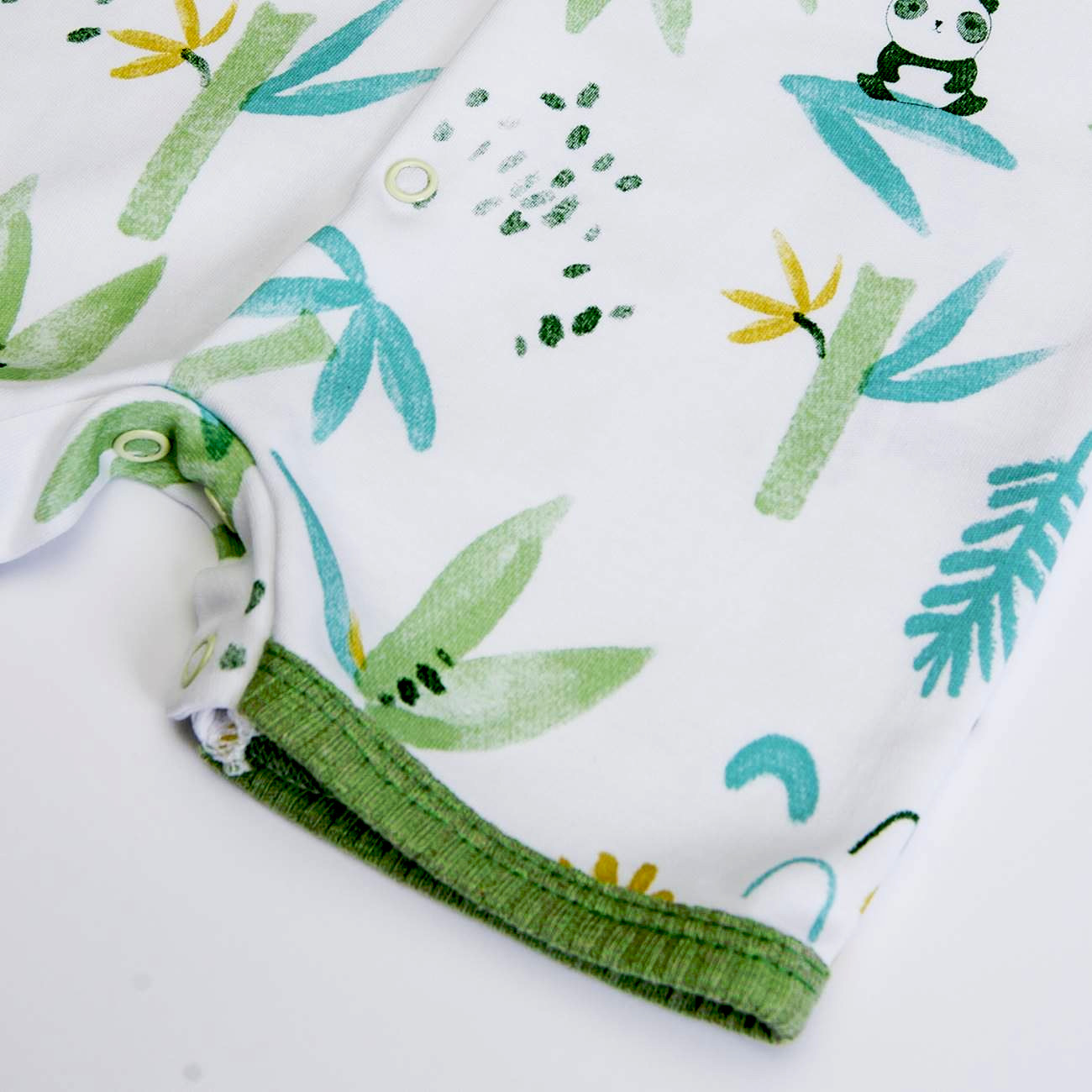 Tecido branco com padrão colorido de bambus, folhas e pandas, bainha verde e botão de pressão