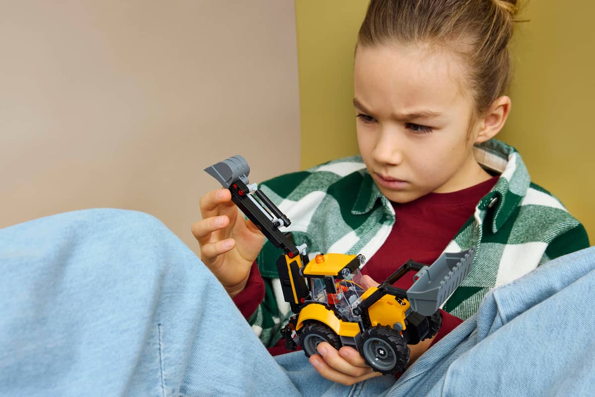 Criança segurando brinquedo escavadora de construção amarelo e preto
