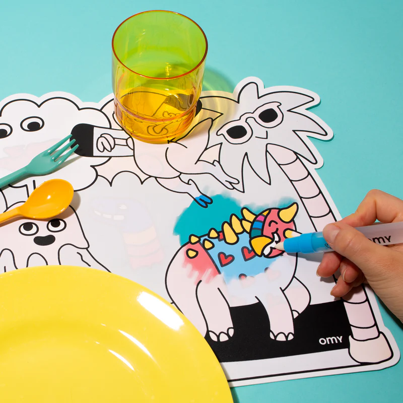Jogo americano para colorir com desenho de dinossauro, garfo, colher, prato amarelo e copo amarelo transparente.