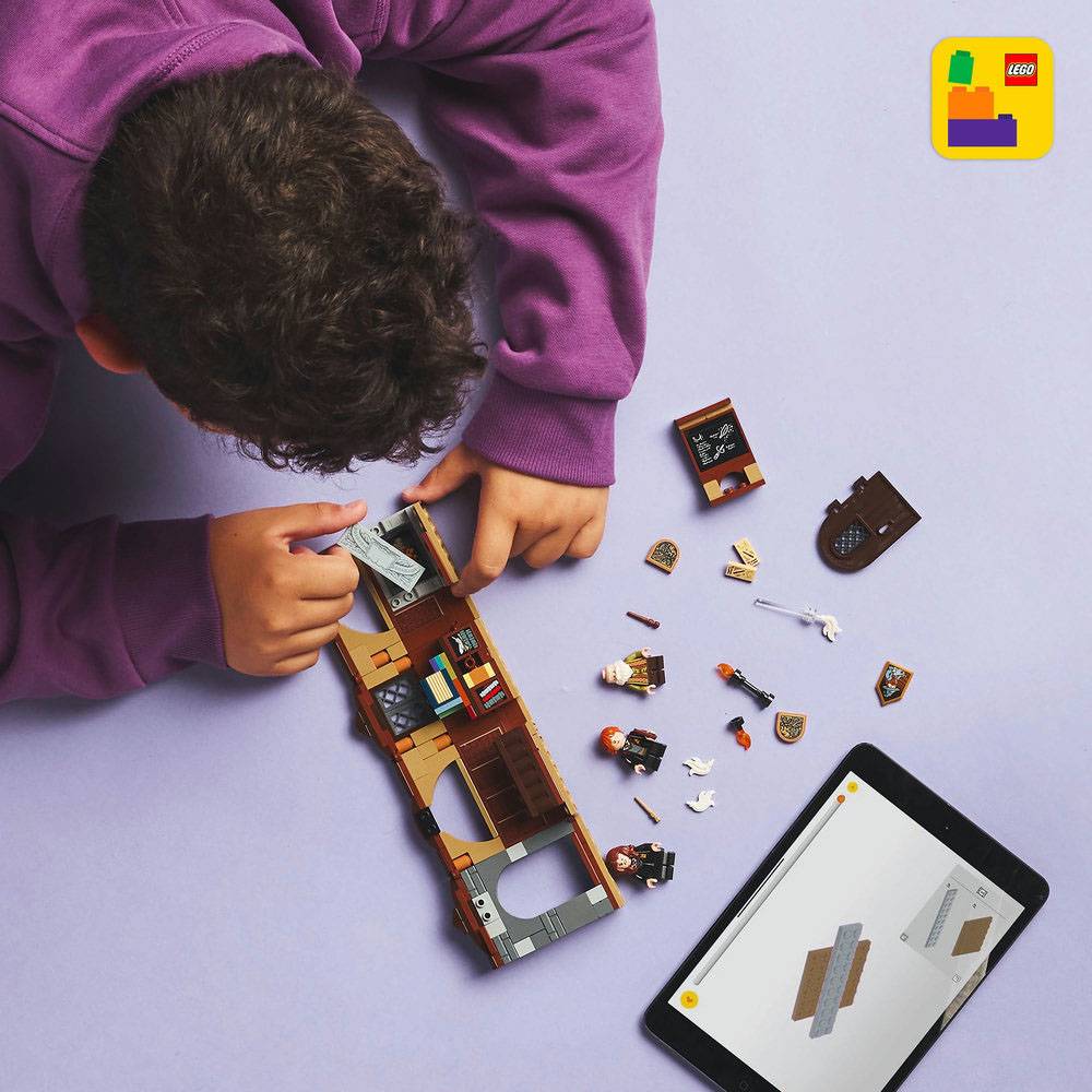 Criança a montar set LEGO castanho com minifiguras e tablet com instruções
