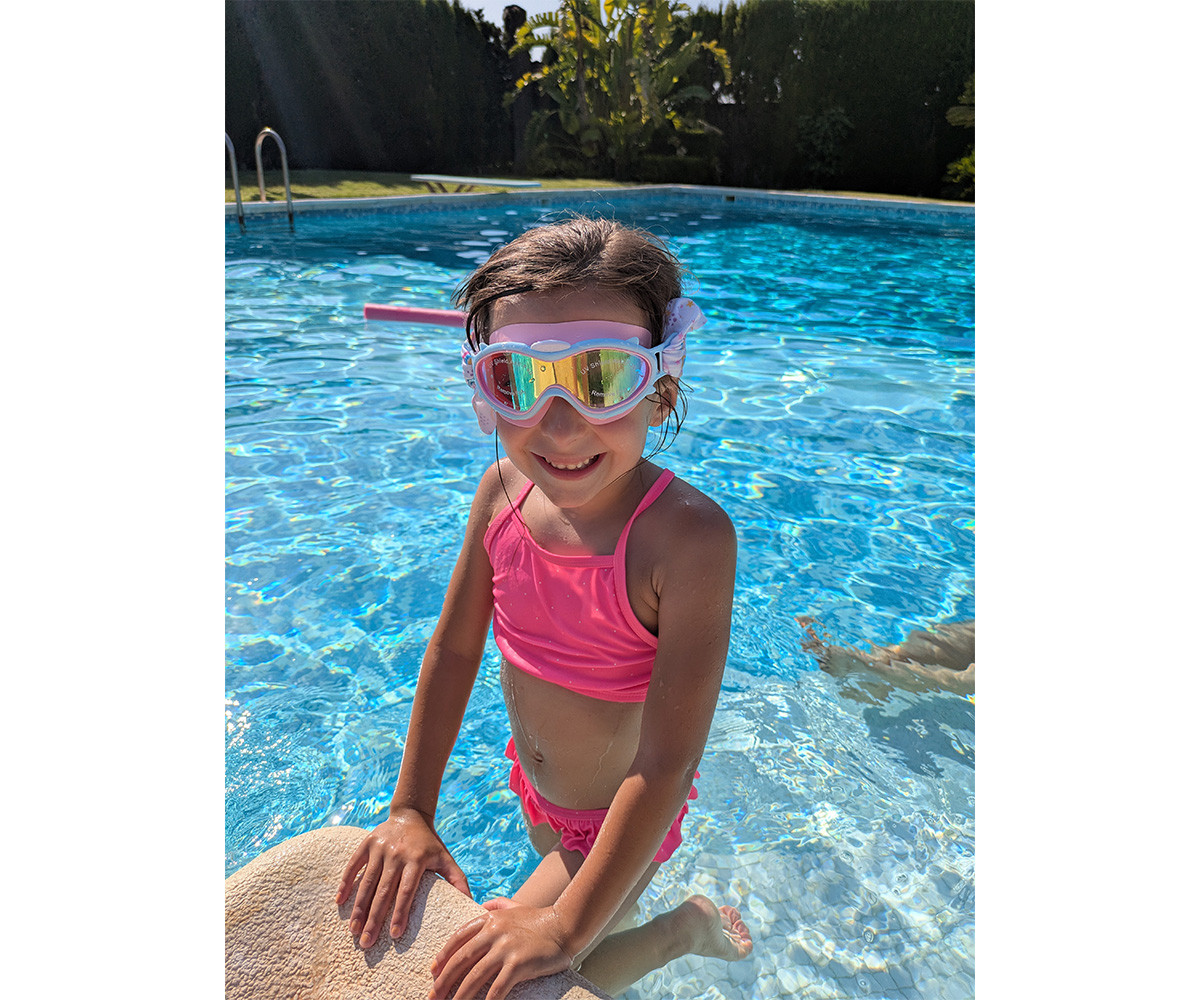 Menina na piscina com fato de banho rosa e óculos de piscina