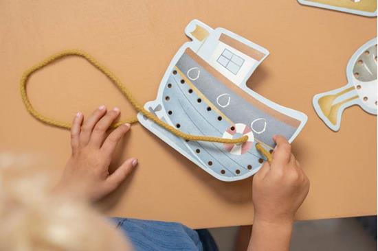Brinquedo de barco em madeira com corda amarela na mão de uma criança