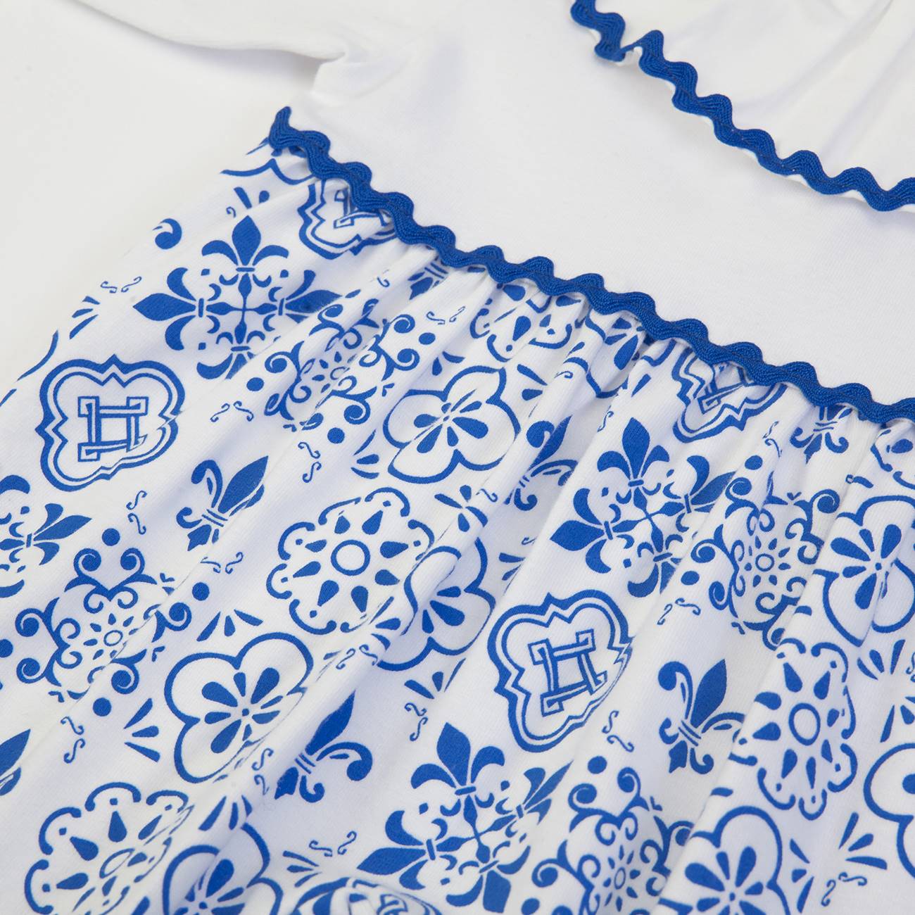 Vestido de bebé branco com padrão azul e detalhes ondulados azuis