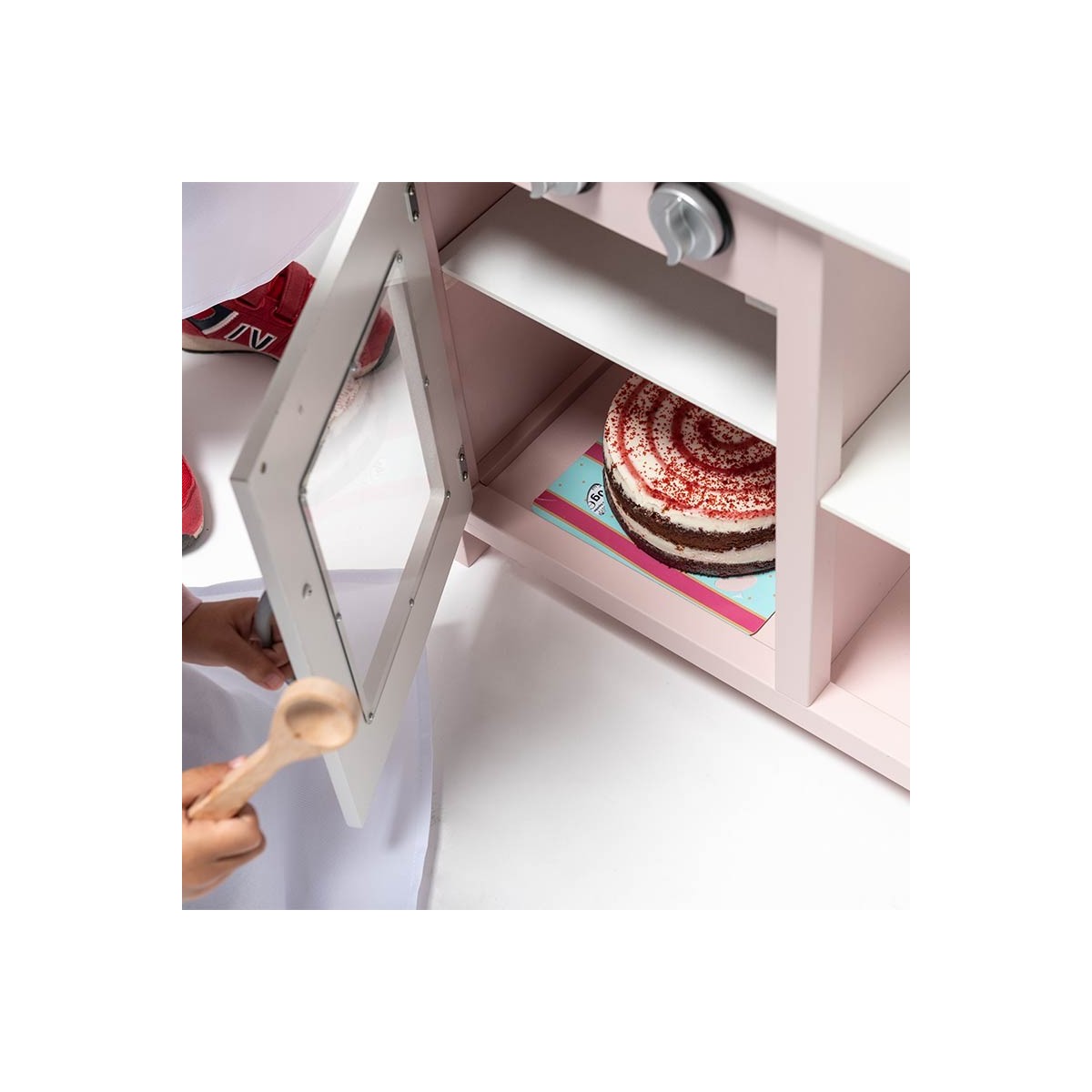 Micro-ondas infantil rosa com bolo falso e criança com colher de pau.