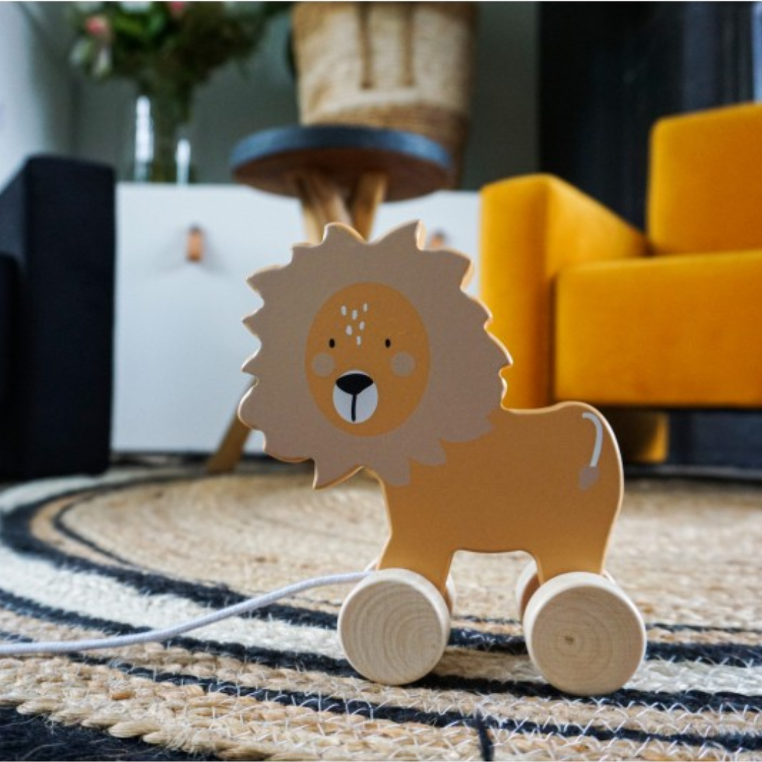 Brinquedo de madeira leão com rodas e cordão sobre tapete trançado