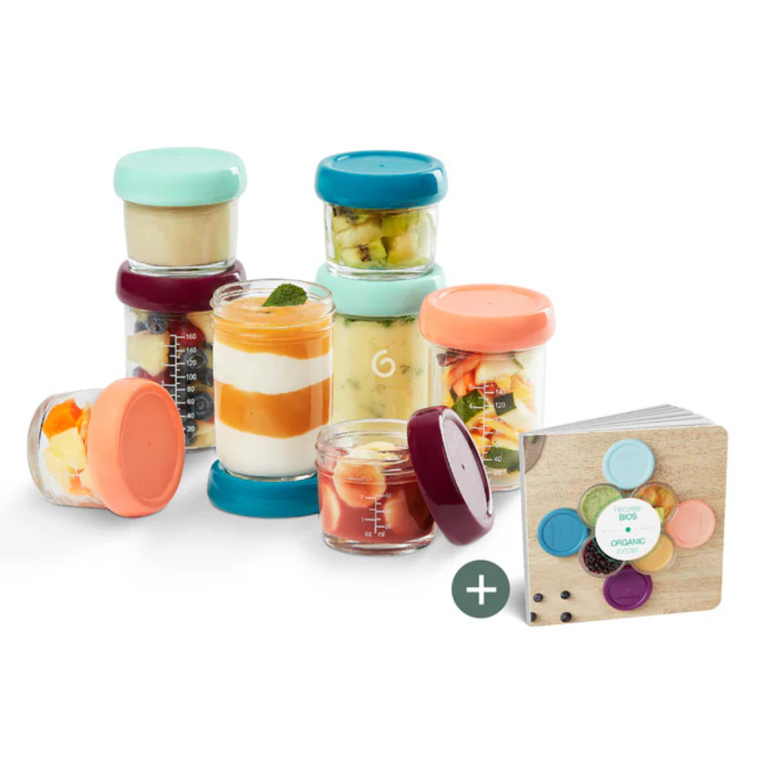 Frascos de vidro com tampas coloridas contendo alimentos e livro de receitas.