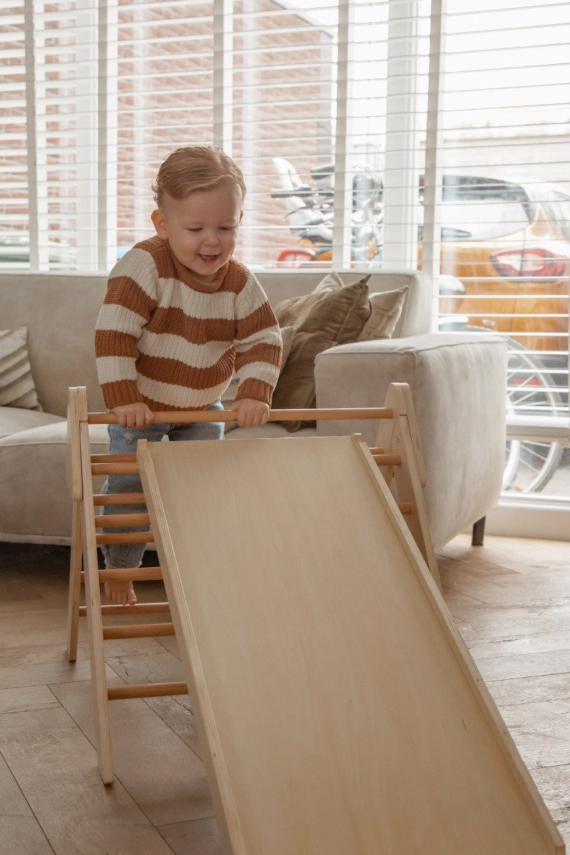 Escorrega de madeira natural para crianças em sala com sofá cinzento