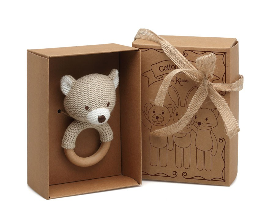 Chocalho de bebé em forma de ursinho bege com argola de madeira em embalagem de cartão castanho com fita de juta.
