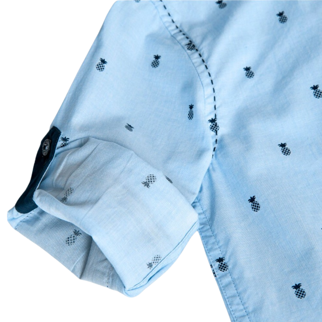 Camisa azul clara com padrão de abacaxis pretos e mangas dobradas