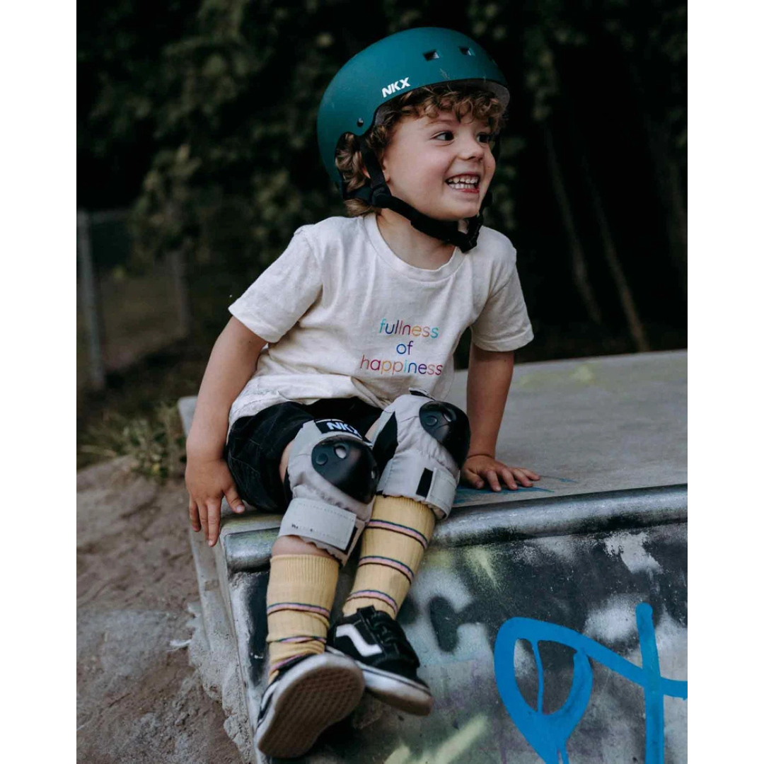 Criança com capacete e joelheiras num skatepark