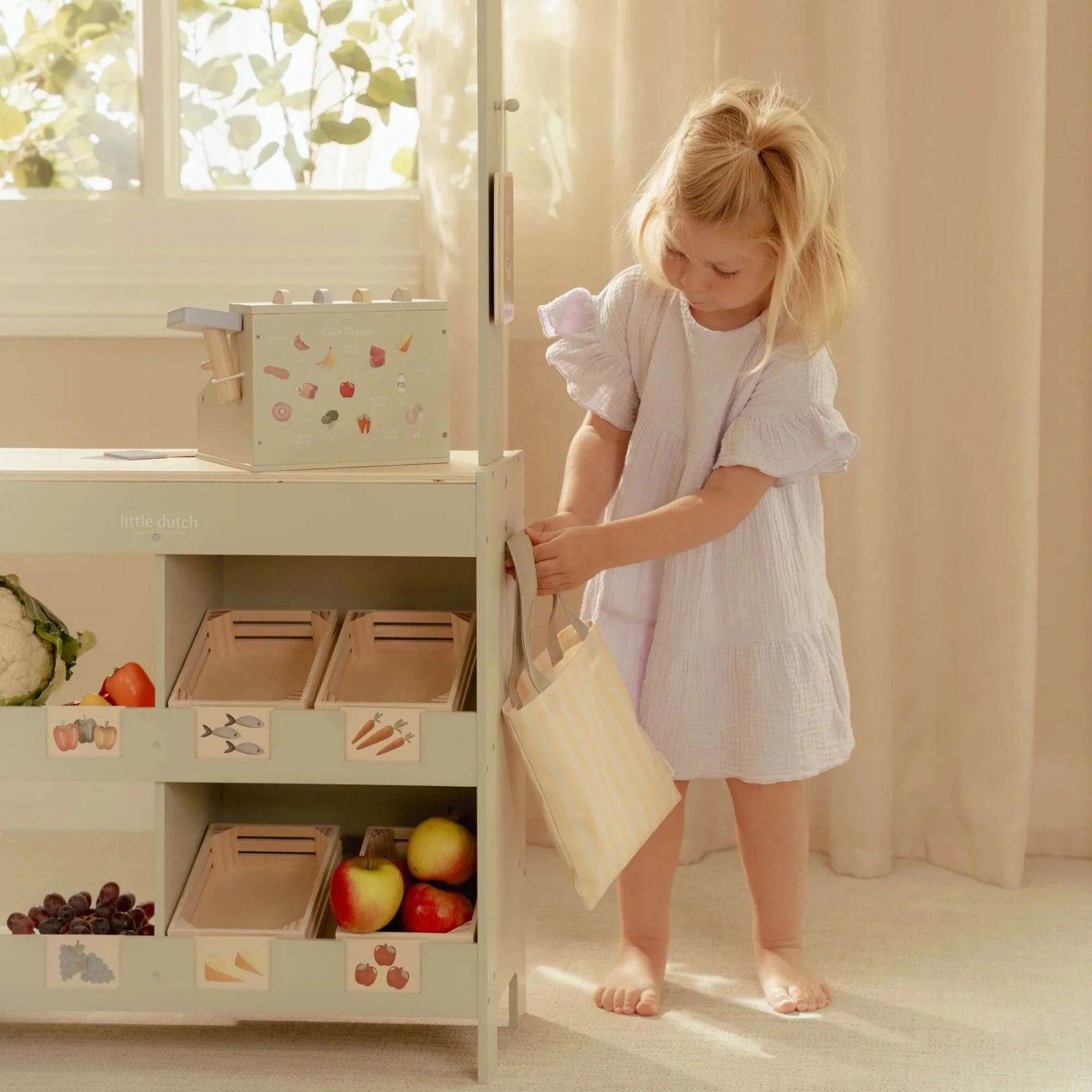 Cozinha de brinquedo verde claro com frutas e menina a brincar