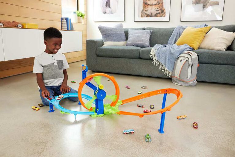 Pista de carrinhos de brinquedo colorida com loop circular em sala com menino e sofá