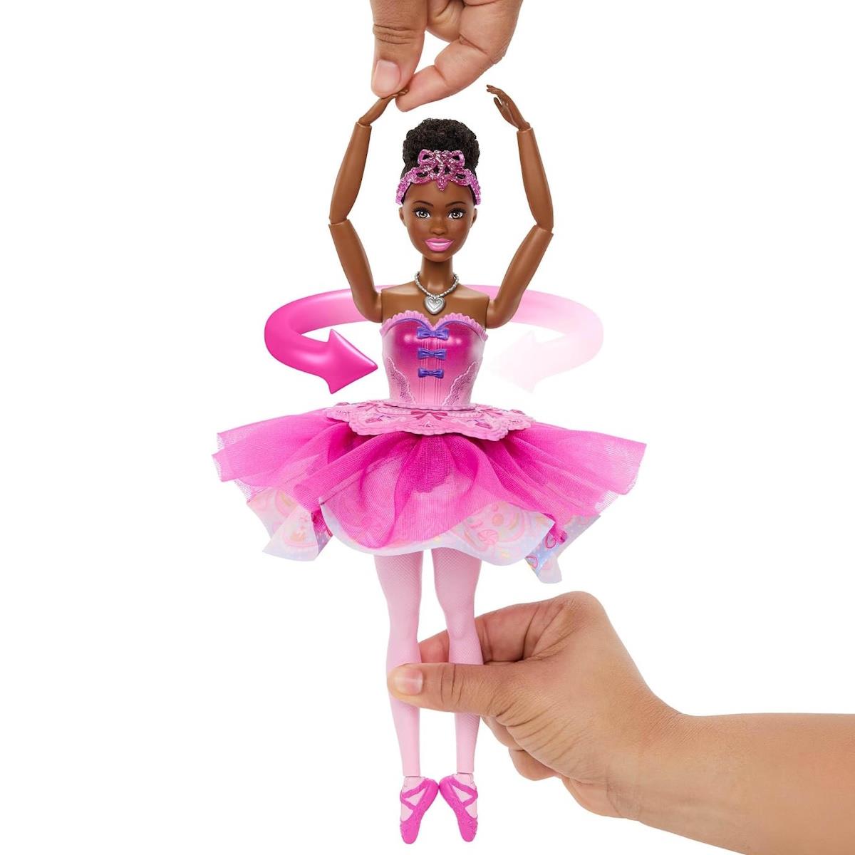 Boneca bailarina com vestido cor-de-rosa segurada por mãos adultas