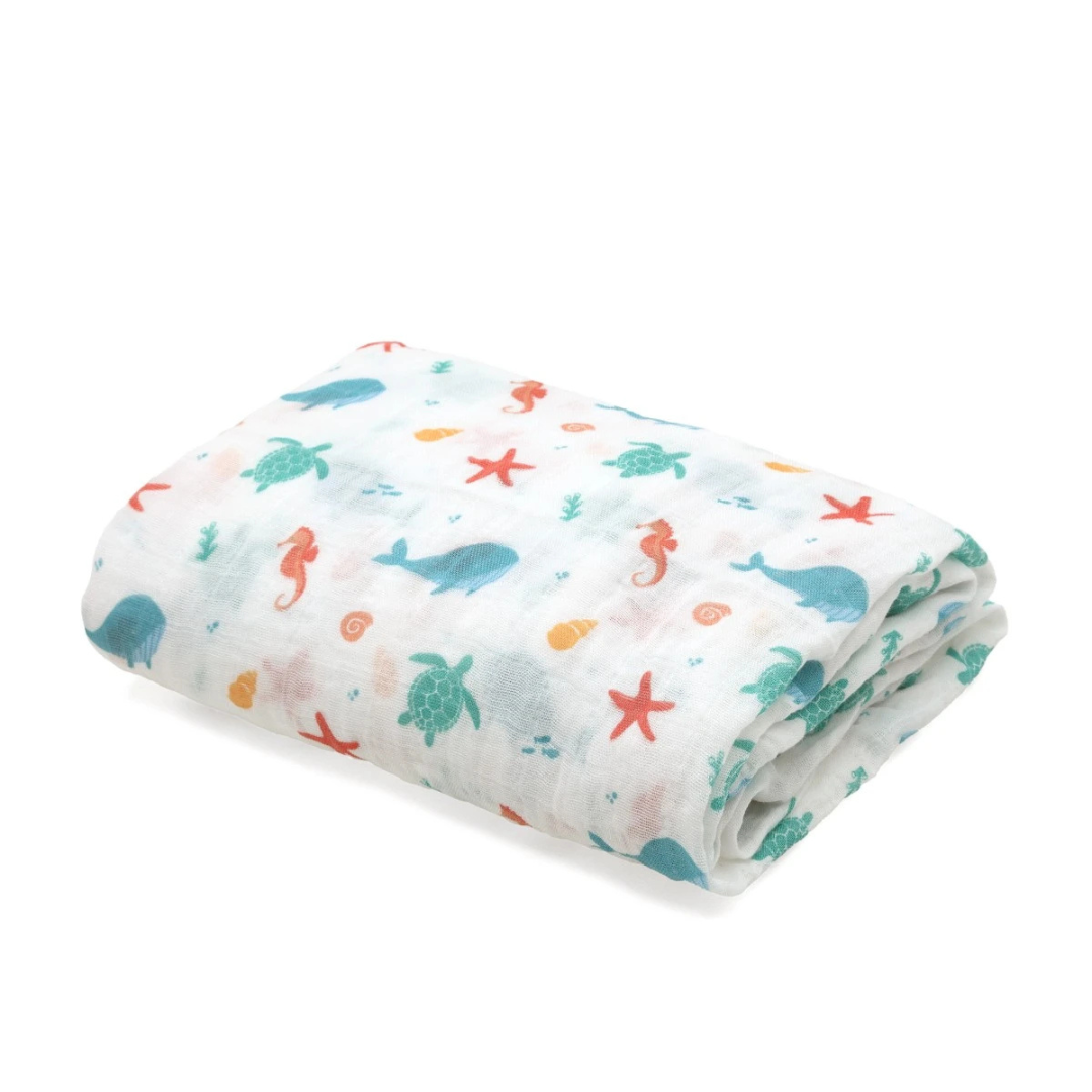Toalha ou manta com padrão de animais marinhos dobrada sobre fundo branco.