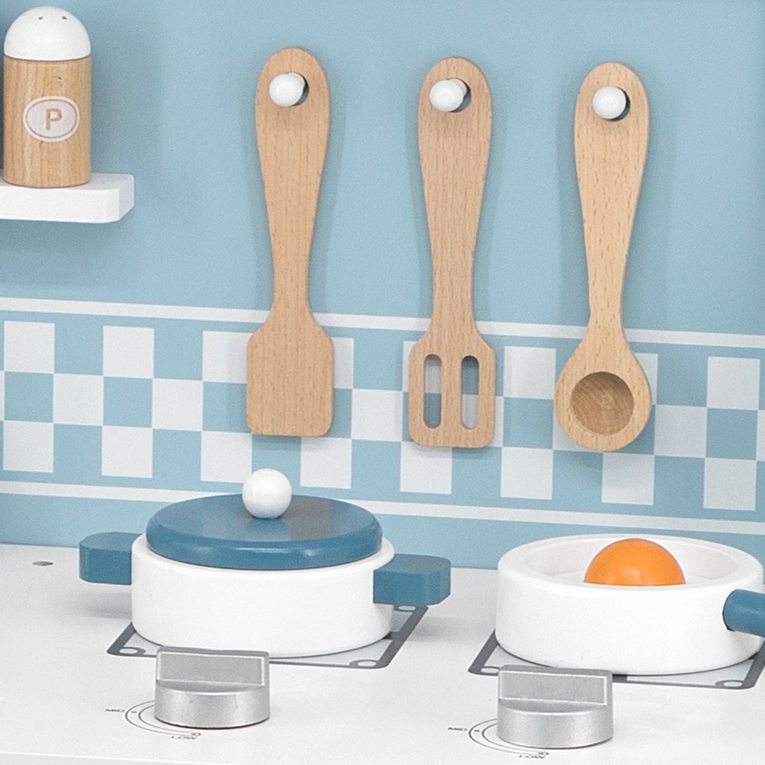 Cozinha de brincar em madeira com utensílios pendurados e panelas com tampa azul
