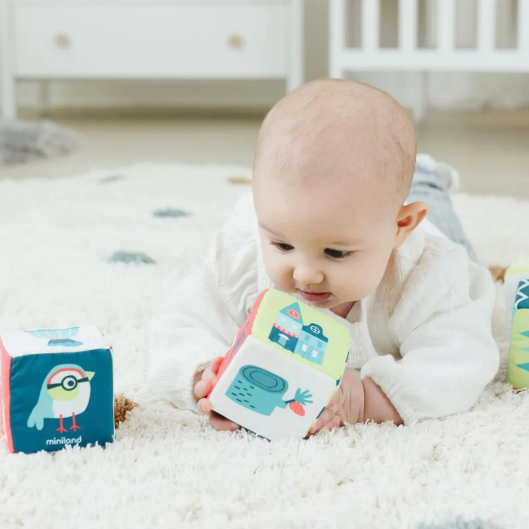 Bebé a brincar com cubos macios coloridos num ambiente interior claro