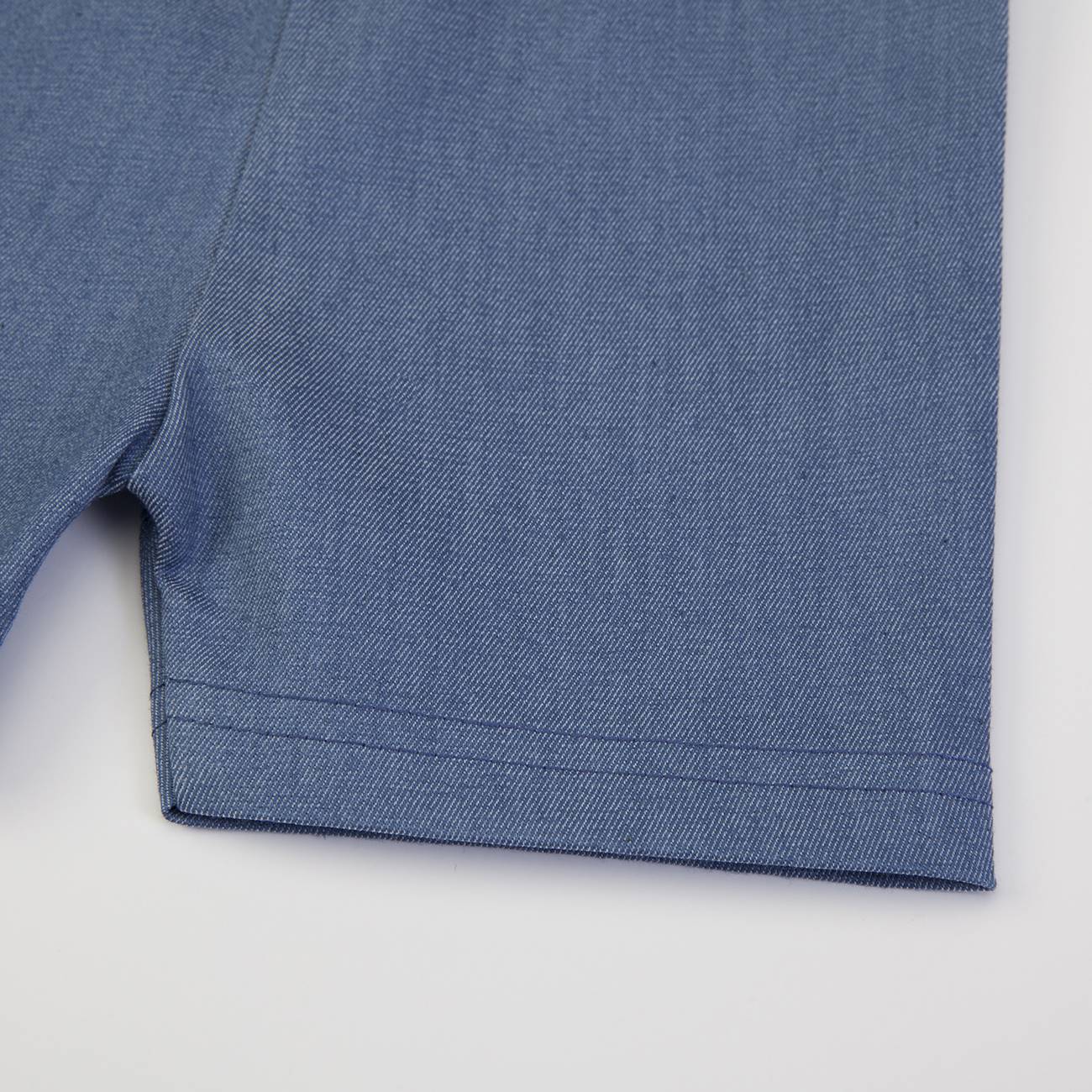 Parte inferior de uma peça de roupa azul com costura dupla na bainha