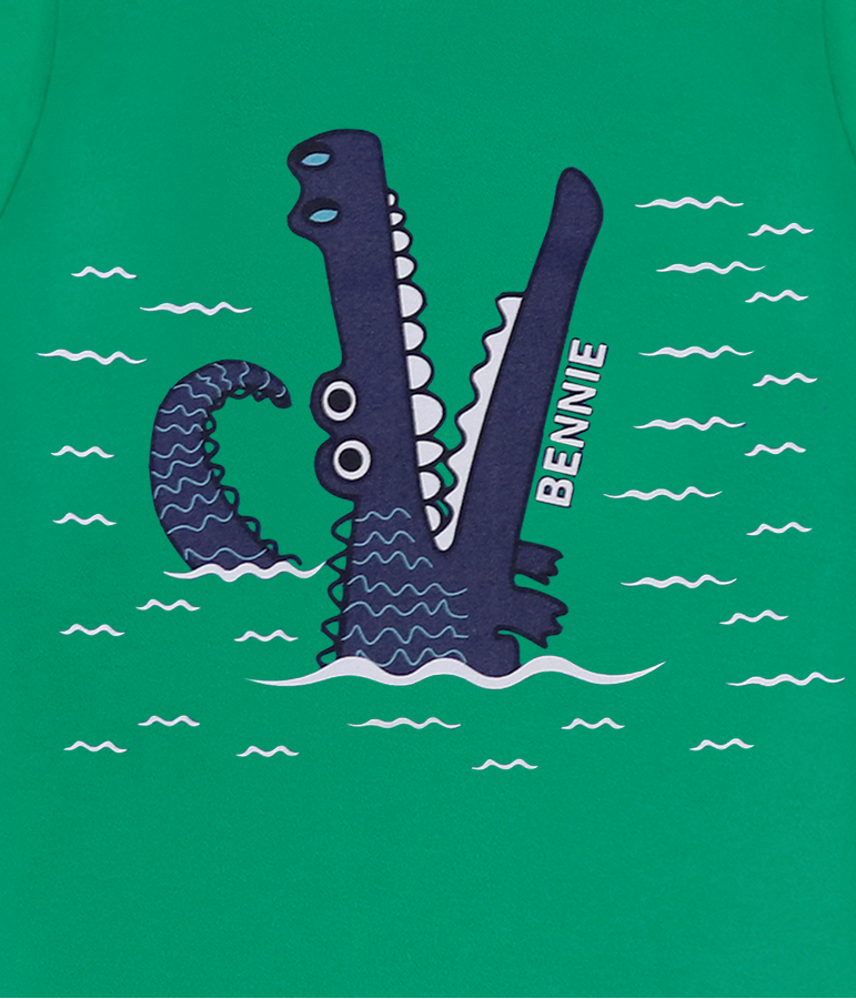 Peça de vestuário verde com estampa de crocodilo azul escuro e texto BENNIE.