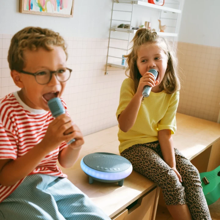 Crianças a cantar com microfones e coluna portátil azul