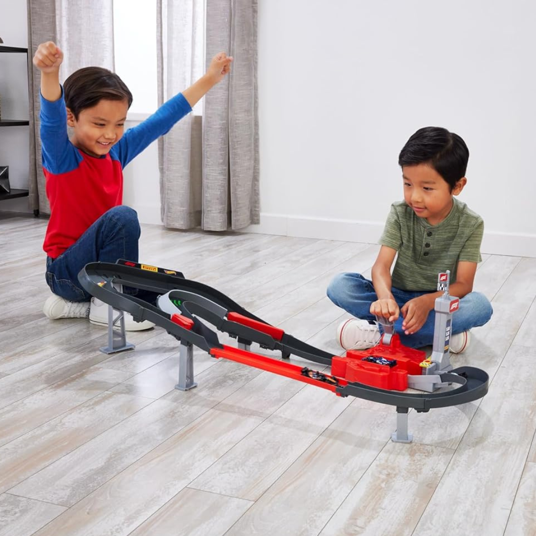 Crianças a jogar com pista de carros de brinquedo preta e vermelha numa sala clara