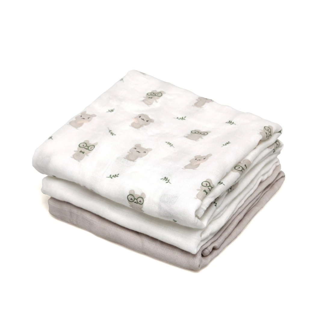 Três toalhas de tecido macio dobradas, duas brancas com padrão de ursos e uma bege.