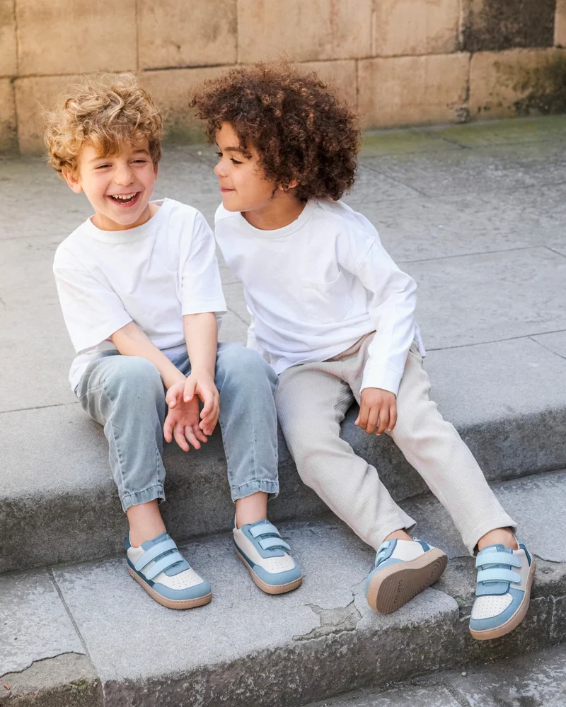 Dois meninos sentados na escadaria usando sapatilhas azul e branco.