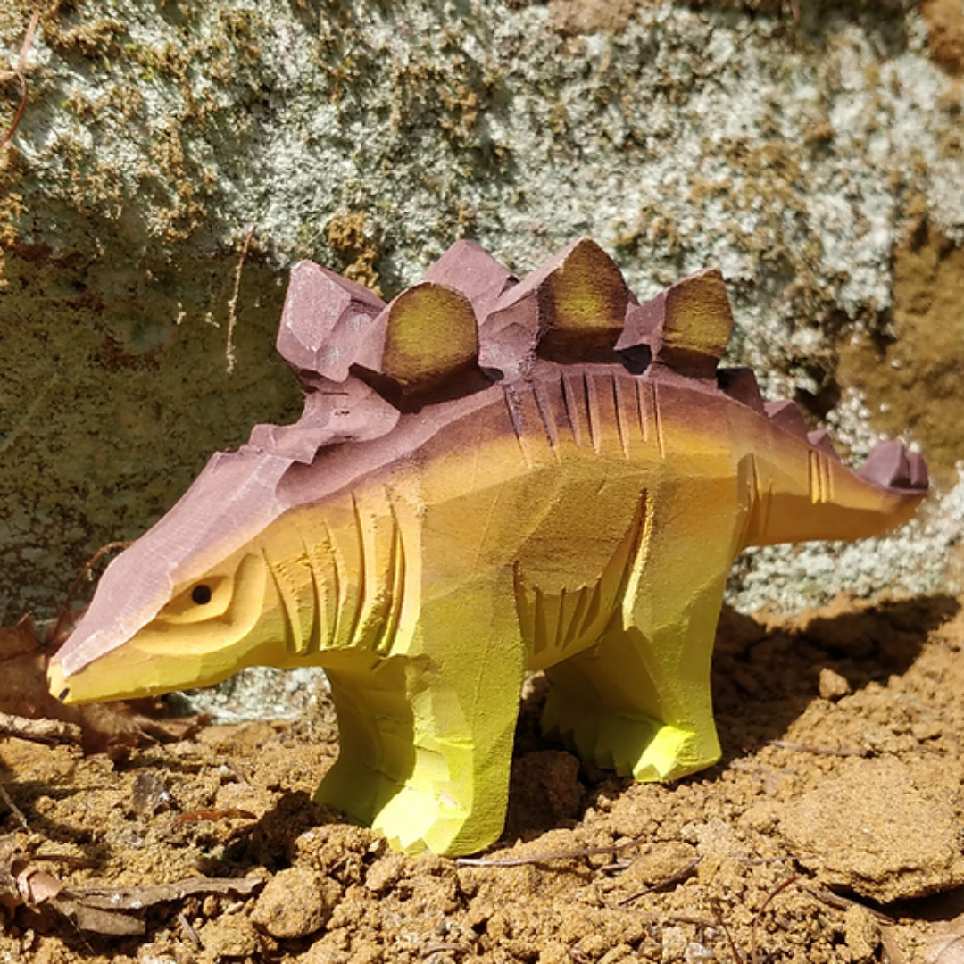 Miniatura de dinossauro stegosaurus em madeira pintada amarelo e roxo com textura entalhada