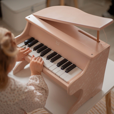 Piano de brinquedo rosa claro com teclas e texto 