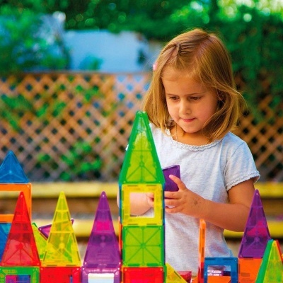Menina a brincar com blocos de construção magnéticos coloridos ao ar livre