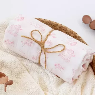 Tecido branco estampado enrolado numa cesta de vime com folhas secas ao lado