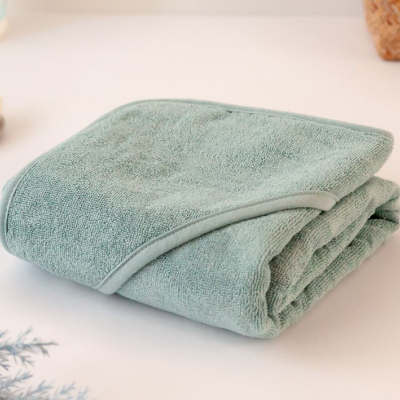 Toalha de banho azul esverdeado dobrada em superfície branca