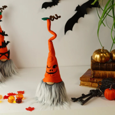 Gnomo decorativo de Halloween com chapéu laranja e barba cinza junto a decoração de outono