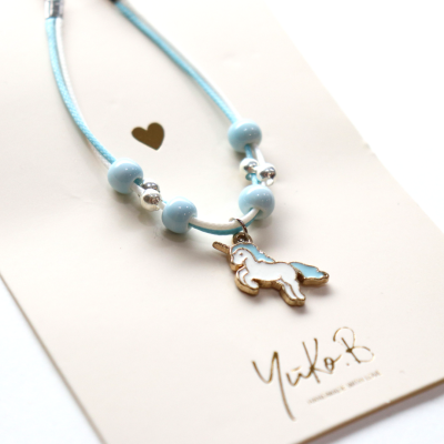 Colar infantil azul com pendente de unicórnio e embalagem branca com texto