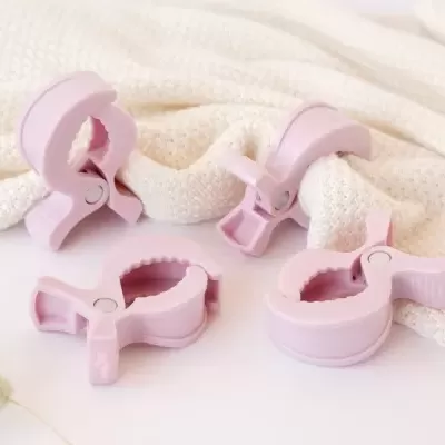 Quatro molas de plástico rosa segurando tecido branco