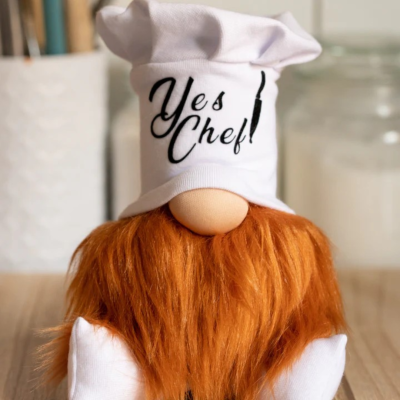 Boneco decorativo de chef com chapéu branco com texto 'Yes Chef!' e barba ruiva