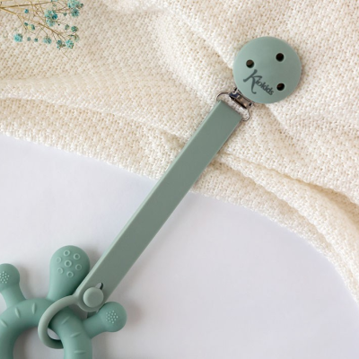 Brinquedo de silicone verde claro com textura e prendedor de fita com texto Kactus sobre tecido amarelo claro