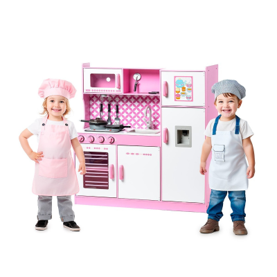 duas crianças com aventais e chapéus de cozinheiro junto a cozinha de brinquedo rosa e branca