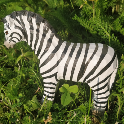 Figurinha decorativa de zebra de madeira com riscas pretas e brancas sobre relva verde