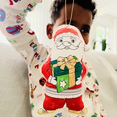 Boneco decorativo de Natal com Pai Natal segurando presente verde em pijama colorido de Natal