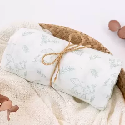 Pano com estampa de elefante e plantas amarrado com corda numa cesta de vime sobre tecido branco