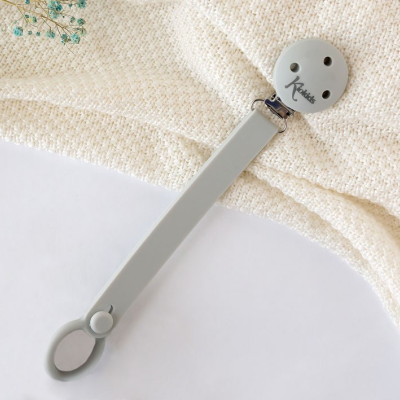 Paleta de silicone cinza claro com botão redondo sobre tecido bege e flores azuis