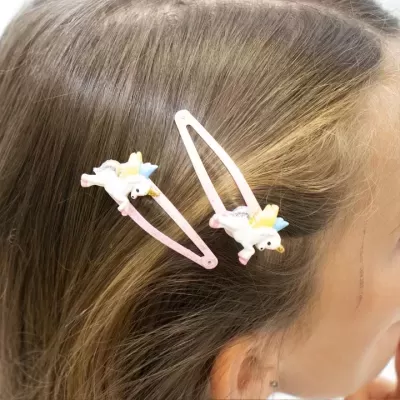 Par de molas de cabelo com unicórnios coloridos em cabelo castanho