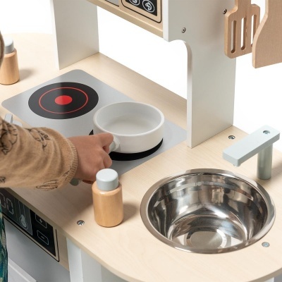 Cozinha de brinquedo em madeira clara com pia metálica, fogão e utensílios de madeira