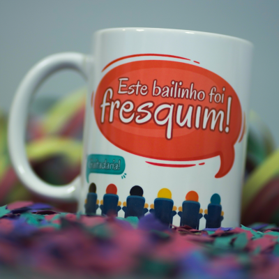 Caneca branca com frase colorida e confetes ao redor
