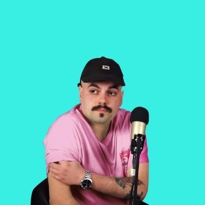 Homem com boné preto, t-shirt rosa e microfone sobre fundo azul-turquesa