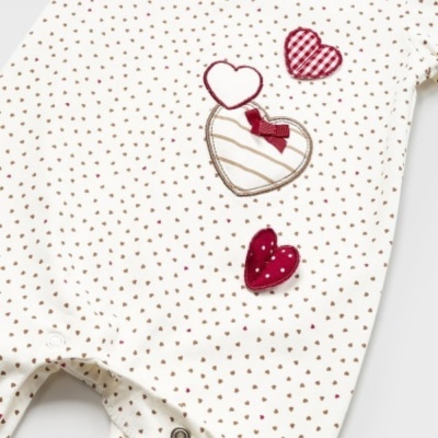 Macacão branco com padrão de pontos castanhos e corações vermelhos aplicados